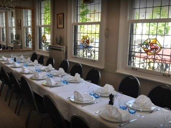 Longue table dressée pour un groupe devant les vitraux, Restaurant François